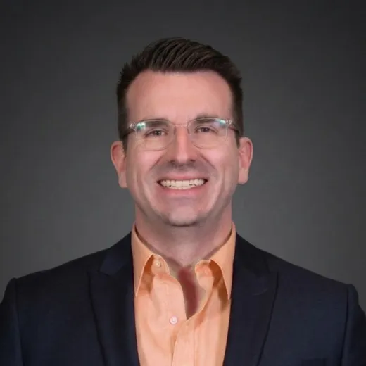 James Spivey in a navy blazer and pink shirt, smiling